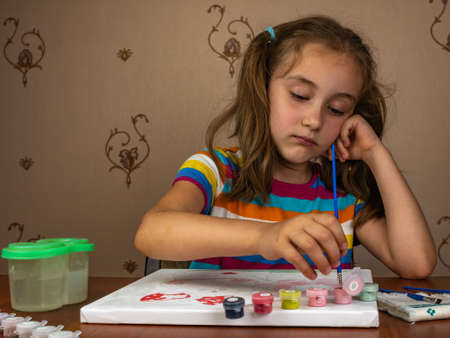 A cute little girl is happy to paint while sitting at the table.の写真素材
