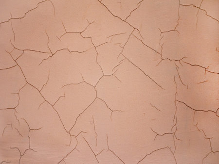 Close-up cracks on an old concrete wall. The wall is painted with beige paint with beautiful cracks....