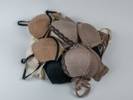 A pile of different classic womens bras on a light background close-up. Underwear beauty, comfort, fashion. Creative beauty concept of womens underwearの写真素材