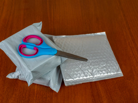 Three parcels and scissors lie on a dark table ready to be opened. Close up of three small parcels...