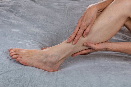 A woman is massaging her legs. Womens feet health care. Spa treatments at home. Close-up of female hands doing reflexology of their legs. Revitalizing foot massage. The concept of female body careの写真素材