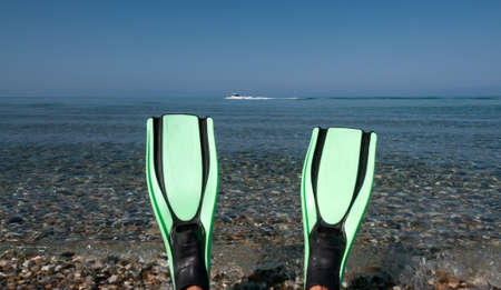 Looking at a blue sea past a pair of fins with a ski boat going pastの写真素材