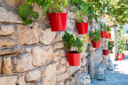Colorful metal flower pots hanging from a stone wallの写真素材