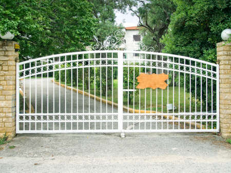 Pair od white steel gates protecting a house.