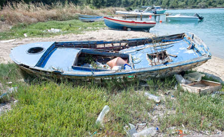 Old wooden boat falling to pieces filled with rubbishの写真素材