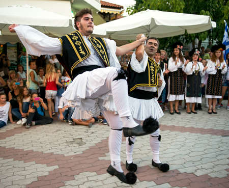 PEFKOHORI , GREECE - SEPTEMBER 19 2014 : Folk Dancers from several countries  taking part in the Annual Folk Dance festival in the village square of Pefkohori ,Greece,The Greek dancers perform their dance.のeditorial素材