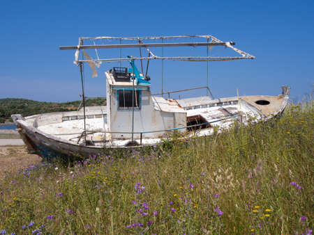 Old fishing boat left to rot on a beachの写真素材