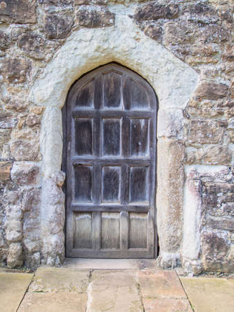Old Wooden Door set in a stone built wall in the side of a houseの写真素材