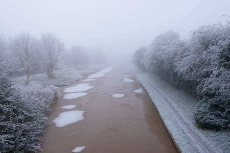 Frozen Canal covered in frost on a cold and foggy Winters dayの写真素材