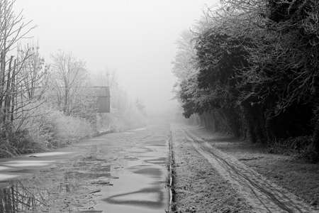 Black and White image of a canal building covered in frost on a cold and foggy Winters dayの写真素材