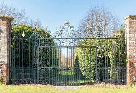 Large pair of metal ornate gates topped with gold leaf.