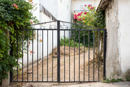 Pair of closed gates protecting a small plot of land between housesの写真素材