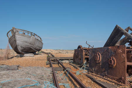 Old wooden fishing boat and a rusty winch on a beach