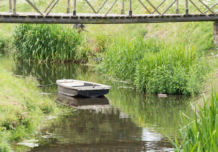 An old wooden rowboat moored in a small stream.の写真素材