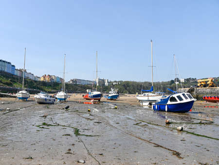 Tenby, Wales - April 15 2019 : The boats in the harbour at Tenby at low tide showing the mooring...