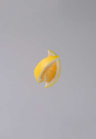 Two slices of yellow grapefruit in the air on a gray background. Life style concept get closer to...