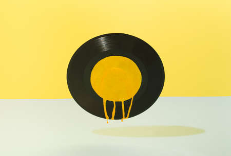 A black gramophone record with yellow paint leaking on a combination of yellow and blue background. Retro concept.の写真素材