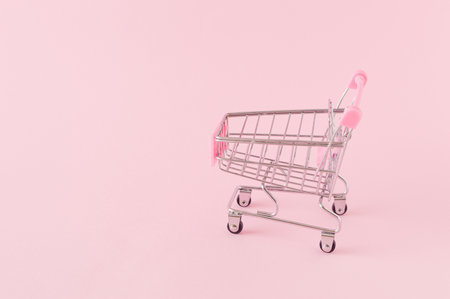 Empty shopping cart on a pink background with a large copy space. Online shopping concept with monochromatic colorsの写真素材
