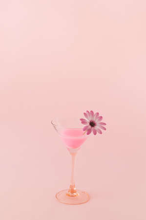 Pink neon drink cocktail on a pink background with a flower in a glass. Monochromatic colors. The concept of a party and celebration with a large copy spaceの写真素材