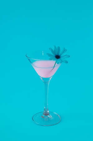 Pink neon drink cocktail with white flowers and all illuminated by blue light. Futuristic party celebration concept with minimal composition.の写真素材