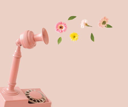 Old retro phone and flowers flying in several colors on a pastel pink background