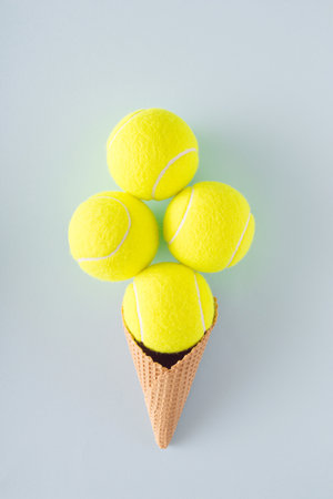 Tennis balls arranged in an ice cream cone on a blue background. Sports competitive tennis conceptの写真素材