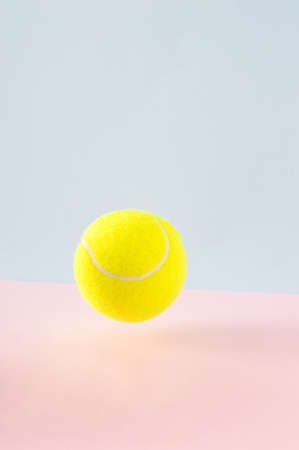 Tennis ball in the air on a combination of blue and pink background. The concept of sports and tennisの写真素材