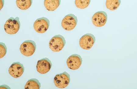 Chocolate chip cookies arranged in a pattern on a turquoise  background. Sweet food concept with copy space.の写真素材