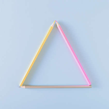 Pink, yellow and gray pencil arranged in a triangle on a blue background. Back to school concept.の写真素材