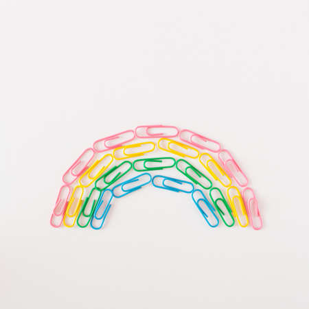Rainbow paperclips arranged in a semicircle on a white background. School concept