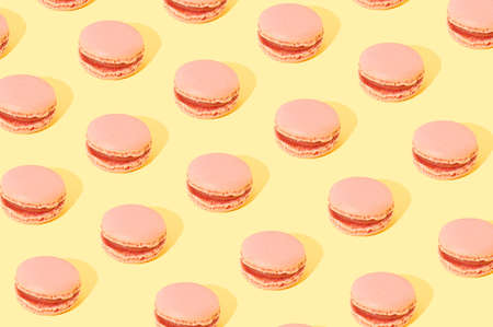 Pink Macarons arranged in a pattern on a yellow background. Sweet food cake conceptの写真素材