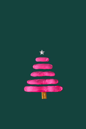 Neon pink color smeared on paper in the shape of a Christmas tree. Silver star on top. Green background. New Year concept.の写真素材