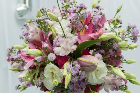 Close up of pink lily flowers around by roses, carnation flowers and green leaves. Close up of...