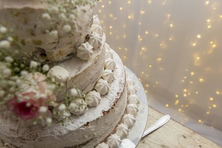 Top view. Close up of beautiful white tree tier cake with fresh flowers with fairly light and...