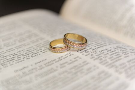 Wedding rings on a holy bible "BÃ­blia Sagrada". Concept of union, love, companionship, faithfulness. Religious union. Selective focus.の写真素材