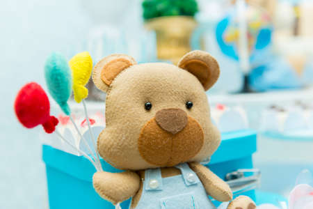 Boy party decoration with teddy bear holding colorful balloons next to luxurious blue ceramic vase with blurred background.の写真素材