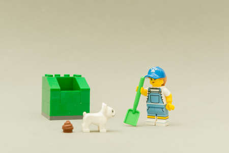 Florianopolis - Brazil, May 5, 2019: Minifigures of a Woman holding a shovel next to a green trash...