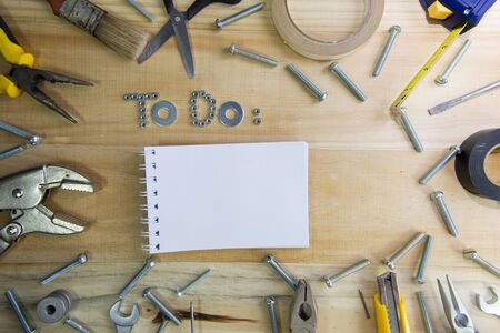 A high angle shot of the phrase to do made of nuts and washers and a blank notebook on a wooden...