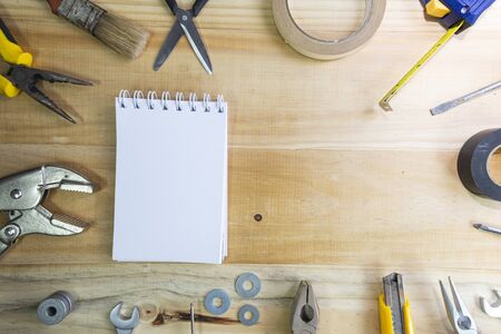 A blank notebook with space for text surrounded by instruments on a wooden surface. construction tools framing wooden background shot from above.の写真素材