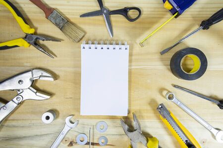A blank notebook with space for text surrounded by instruments on a wooden surface. construction...