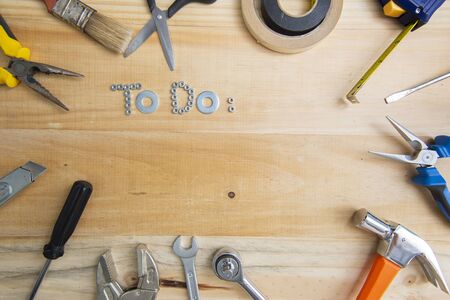 A high angle shot of the phrase "to do" made of screws surrounded by instruments on a wooden surface for planning the workの写真素材