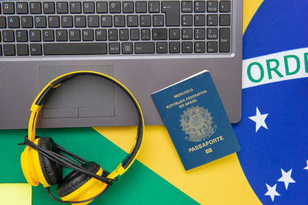 Top view of travel objects: Brazilian passport, yellow headphones and notebook on Brazilian flag in the background. Travel concept. Immigration and emigration, tourism and international travel.の写真素材