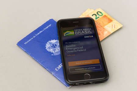 Florianopolis, Brazil, June 27, 2020: Top view of printed and digital work card on white background. Concept of formal work and government benefits. Work and social security.のeditorial素材