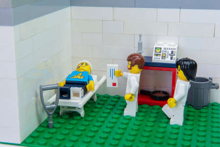 Florianopolis, Brazil. September 19, 2020: Doctor minifigure delivering prescription medication for pain relief to patient lying on stretcher in hospital after a car accident.のeditorial素材