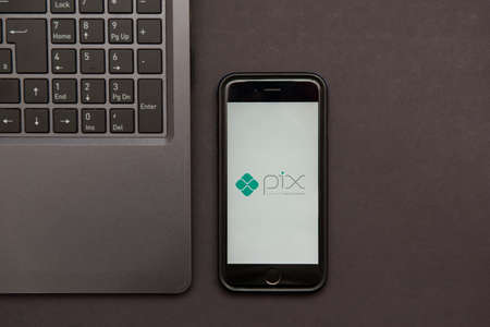 Florianopolis, Brazil. 09/28/2020: Top view of Pix logo on smartphone screen and notebook on the black table. Pix, new Brazilian electronic payment system. Brazilian Central Bank. Copy space.のeditorial素材