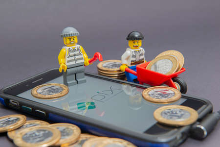 Florianopolis, Brazil. 10/7/2020: Thieves minifigure stealing money from PIX on smartphone screen. Fraud concept with the Central Bank of Brazil instant payment system. Selective focus. Copy space.のeditorial素材