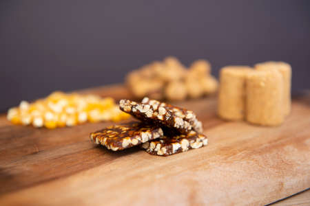 Typical brazilian June Party (Festa Junina) foods on a wooden table: peanuts candies with kernels,...