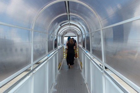 Campinas, Viracopos Airport, Brazil - March 24, 2022: back view of passengers on the plane's access stairs. Staircase covered in acrylic forming an access tunnel to the small plane in the airportのeditorial素材