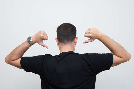 Back view of man has raised arms, and their fingers point to their backs