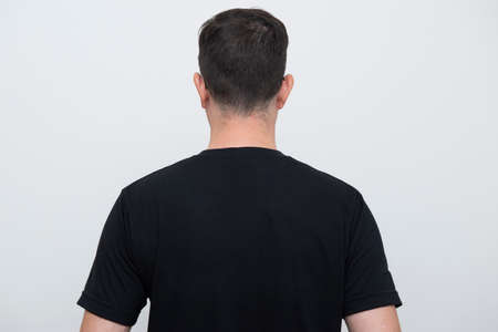 Back view of man wearing black t-shirt on white background. Copy space.の写真素材